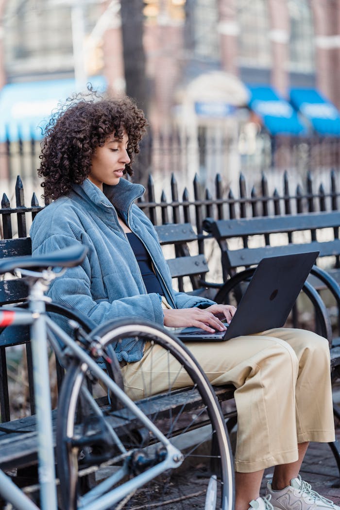 Focused young ethnic female freelancer working distantly on netbook in park